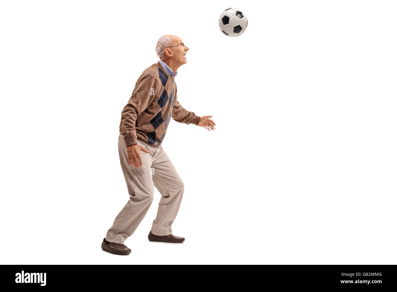 serious elderly doctor holds a soccer ball in one hand and points