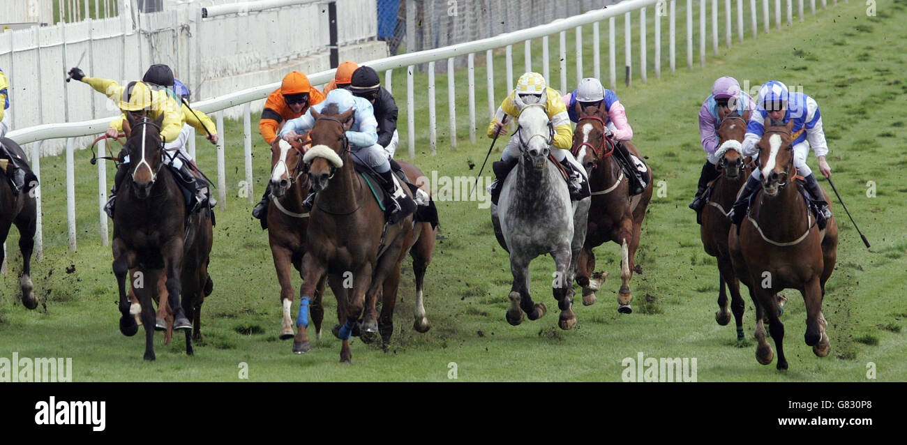 Bishops Court (centre in light blue) ridden by Sebastian Sanders goes on to win the Blue Square Handicap Stakes, followed by Hidden Dragon ridden by Robert Winston (right in royal blue) and Cape Royal ridden by Kevin Darley (Left in Yellow and Black). Stock Photo