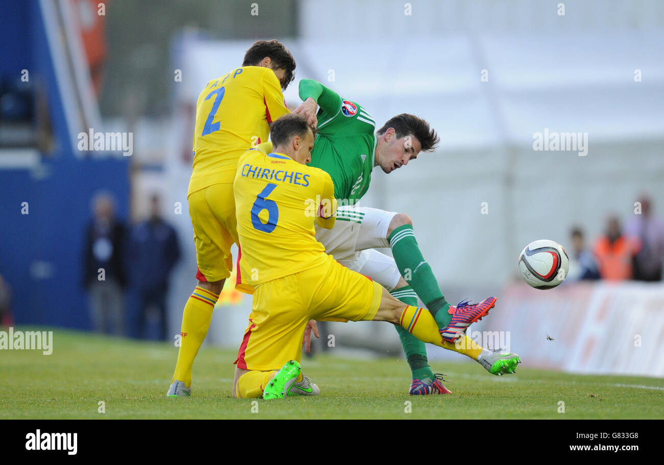 Northern Ireland's Kyle Lafferty and Romania's Vlad Chiriches (centre) and Paul Papp (left) battle for the ball during the UEFA European Championship Qualifying game at Windsor Park, Belfast. Stock Photo