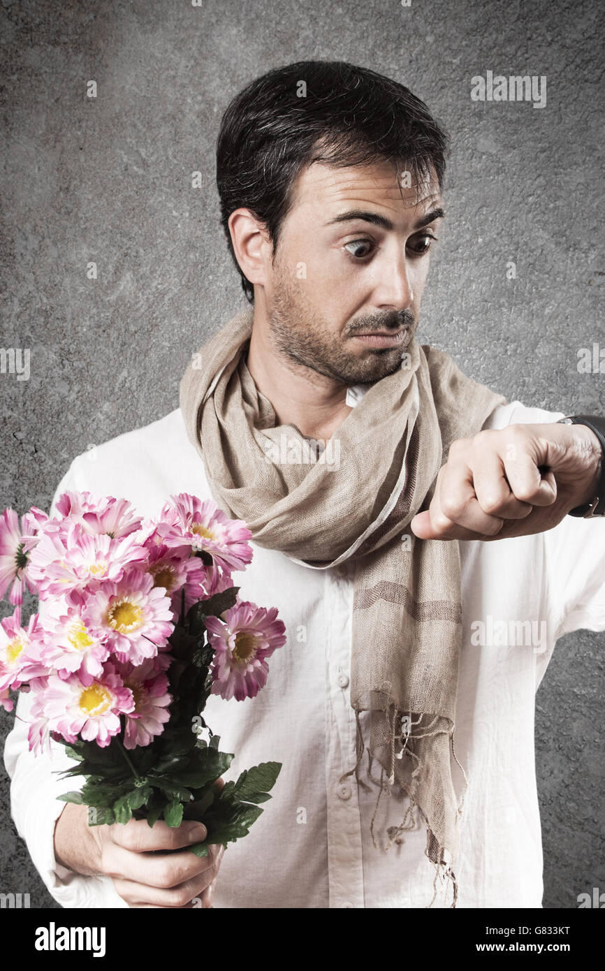 Man in love with a bouquet of flowers looking watch with concern. Vertical image. Stock Photo