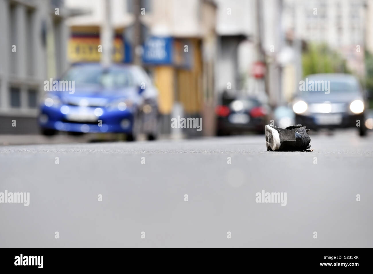 Shoe on the street with cars in background after victim was hit by vehicle Stock Photo