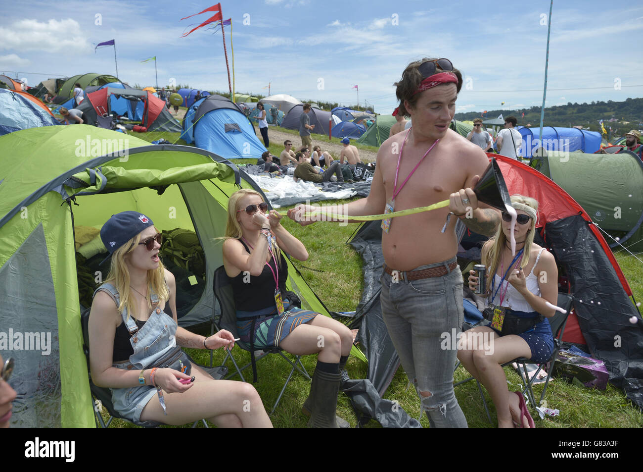 Chloe, 22, (surname not given) drunks fruit cider through a funnel and tube, also known as 'chugging' at the Glastonbury Festival, at Worthy Farm in Somerset. Stock Photo