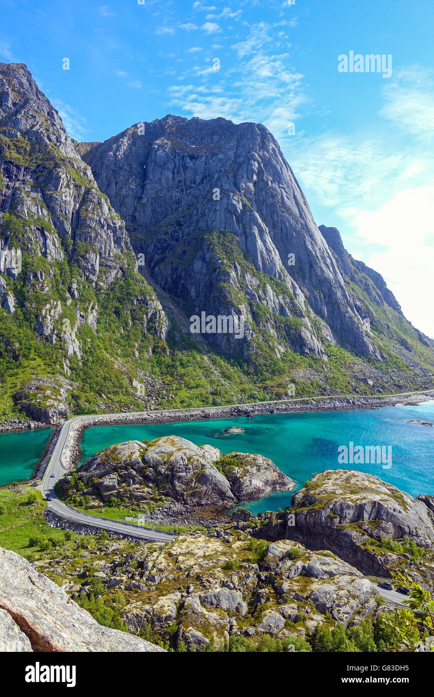 Narrow road between sea and mountains, Henningsvaer, Lofoten, with blue sea dn causeway Stock Photo