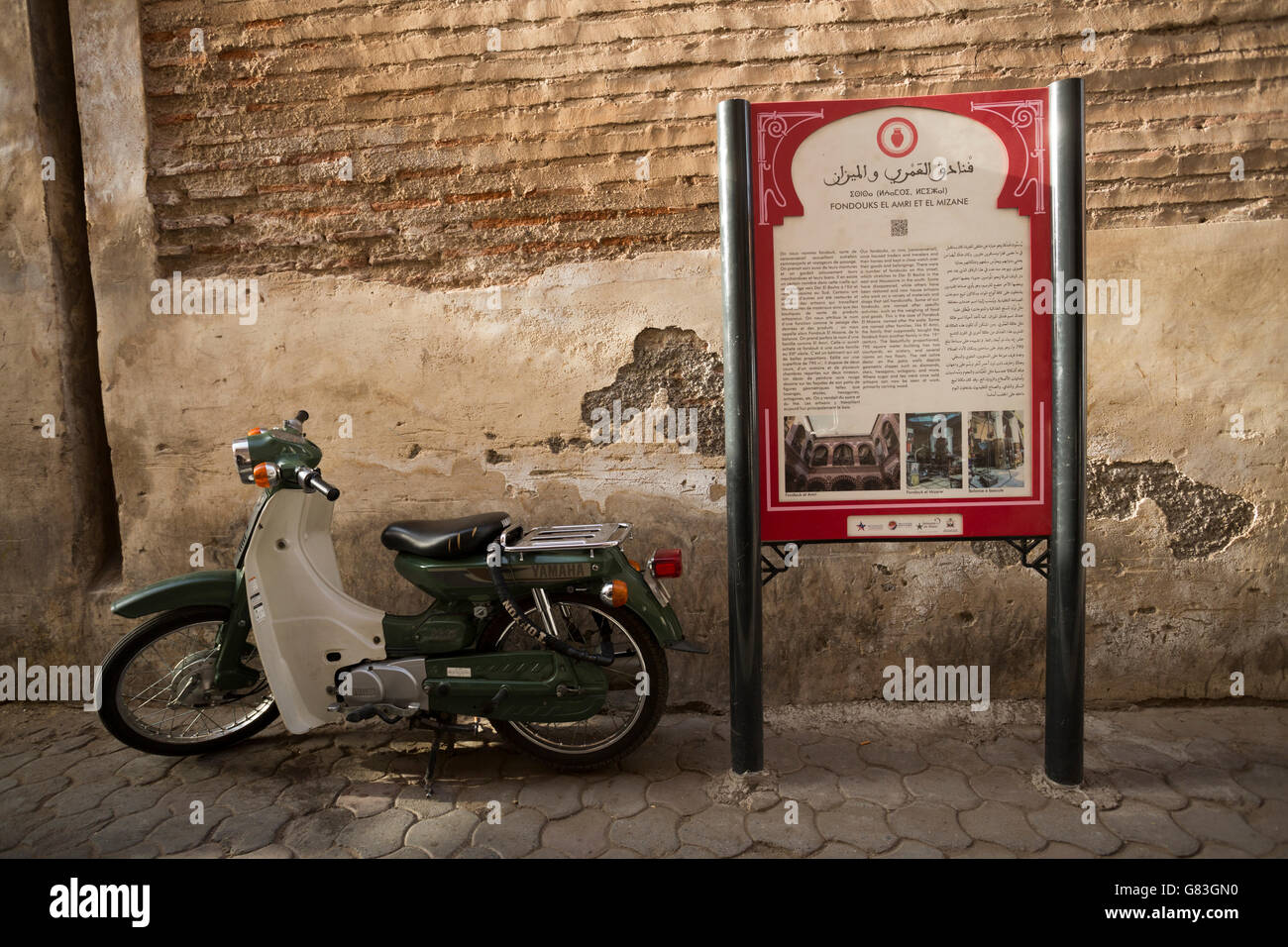 A cultural site marker stands along a narrow street in the Marrakesh Medina, Morocco. Stock Photo