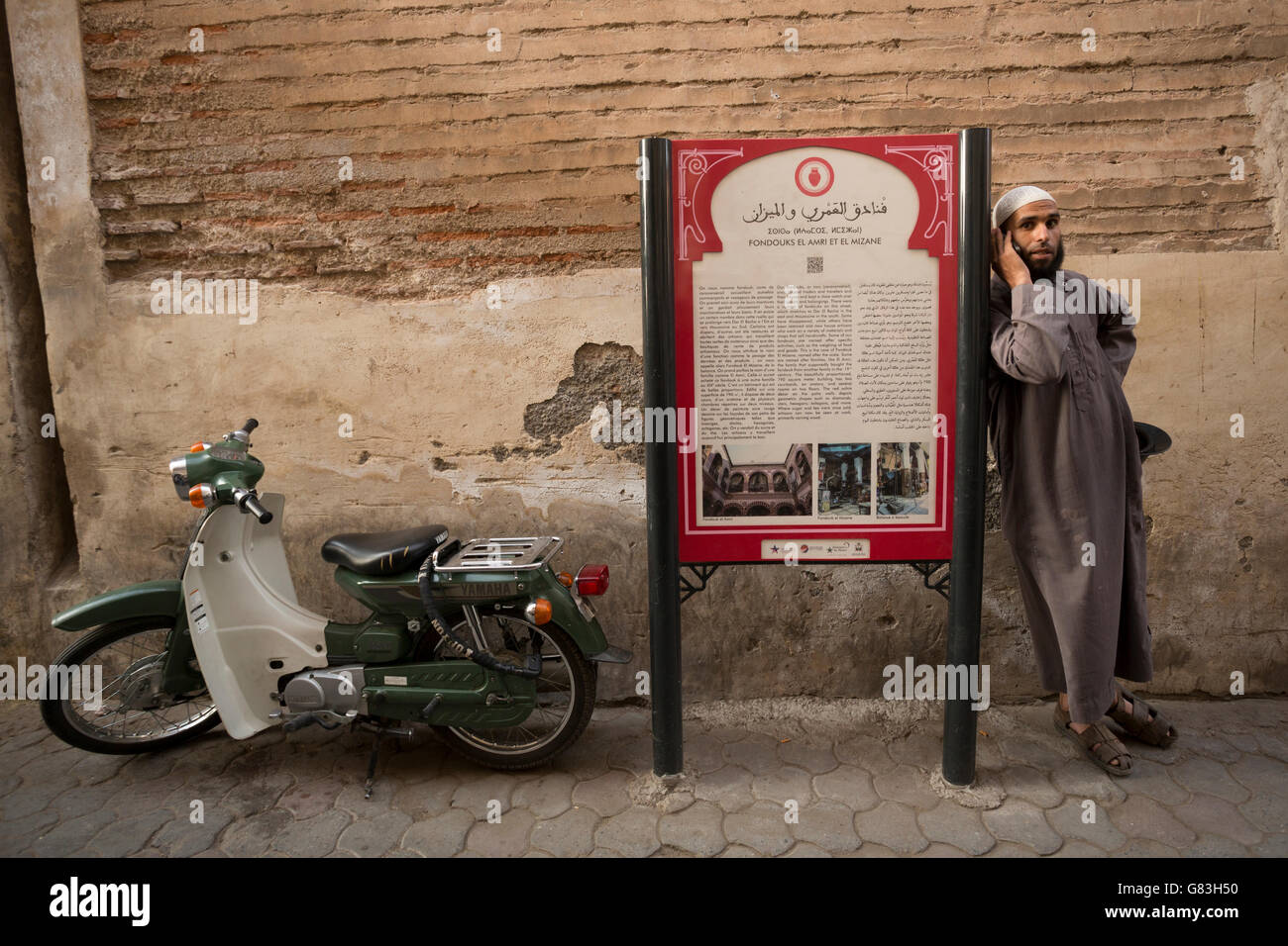 A cultural site marker stands along a narrow street in the Marrakesh Medina, Morocco. Stock Photo
