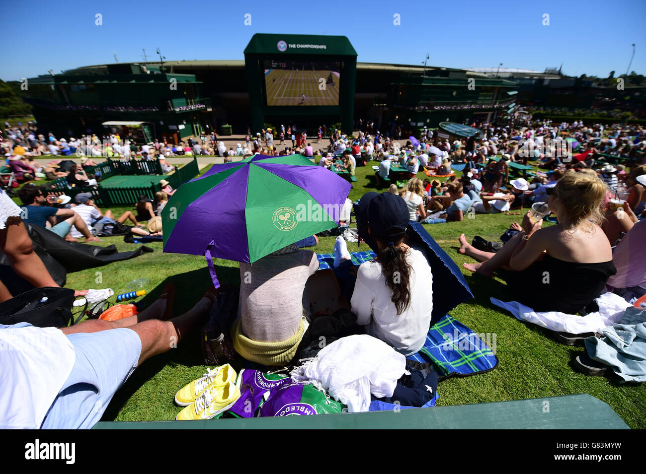 Spectators shield from the sun on Murray Mount during day two of the Wimbledon Championships at the All England Lawn Tennis and Croquet Club, Wimbledon. Stock Photo