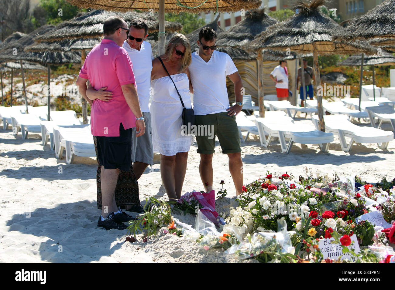People pay their respects on the beach near the RIU Imperial Marhaba hotel in Sousse, Tunisia, as British holidaymakers defy the terrorists and continue to stay in Sousse despite the bloodbath on the beach. PRESS ASSOCIATION Photo. Picture date: Tuesday June 30, 2015. The sands at Sousse were quiet and calm today as tourists and locals alike continued to pay their respects to the 38 dead outside the RIU Imperial Marhaba and Bellevue hotels. Flowers continue to be laid at three heart-shaped memorials that mark where so many people lost their lives, with many people in tears as they read the Stock Photo