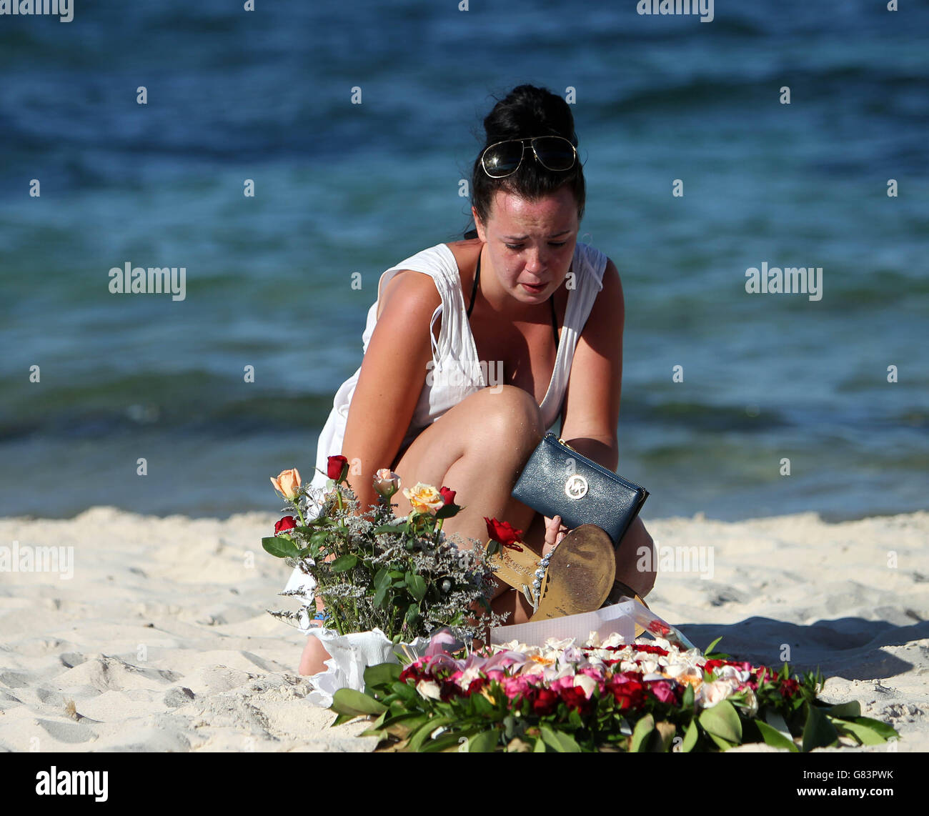 A woman looks at floral tributes on the beach near the RIU Imperial Marhaba hotel in Sousse, Tunisia, as British holidaymakers defy the terrorists and continue to stay in Sousse despite the bloodbath on the beach. PRESS ASSOCIATION Photo. Picture date: Tuesday June 30, 2015. The sands at Sousse were quiet and calm today as tourists and locals alike continued to pay their respects to the 38 dead outside the RIU Imperial Marhaba and Bellevue hotels. Flowers continue to be laid at three heart-shaped memorials that mark where so many people lost their lives, with many people in tears as theyy Stock Photo