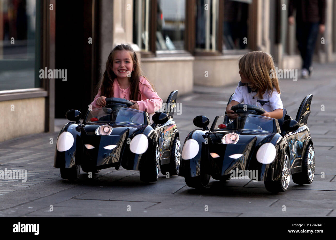 Four-year-olds Emee (left) and Teddy (no surnames given) play with the Batman 6v Battery Powered Batmobile as Hamleys launches its Christmas toy range in central London. Even the youngest children will need their technological know-how up to speed when Father Christmas visits this year, according to the top toy predictions from Hamleys. Stock Photo