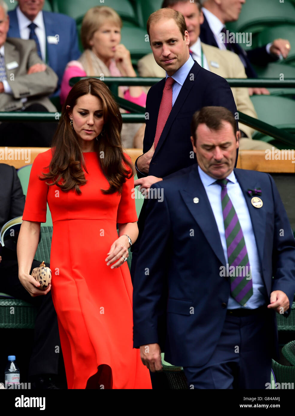 The Duke and Duchess of Cambridge are led their seats by Chairman of the AELTC Philip Brook (left) in the Royal Box on day Nine of the Wimbledon Championships at the All England Lawn Tennis and Croquet Club, Wimbledon. Stock Photo
