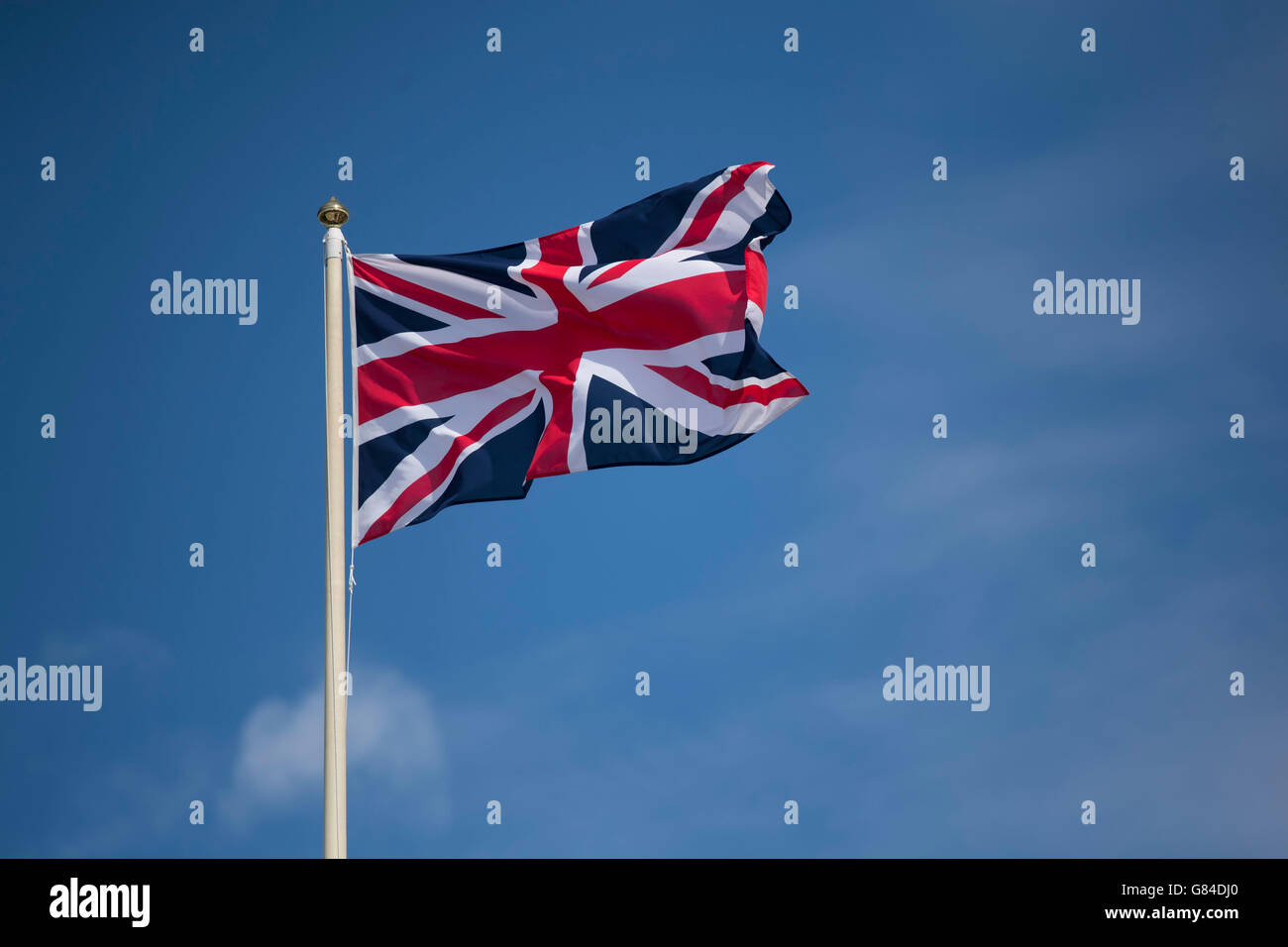 Union Jack flag of the United Kingdom blowing in the wind against a blue sky. Stock Photo