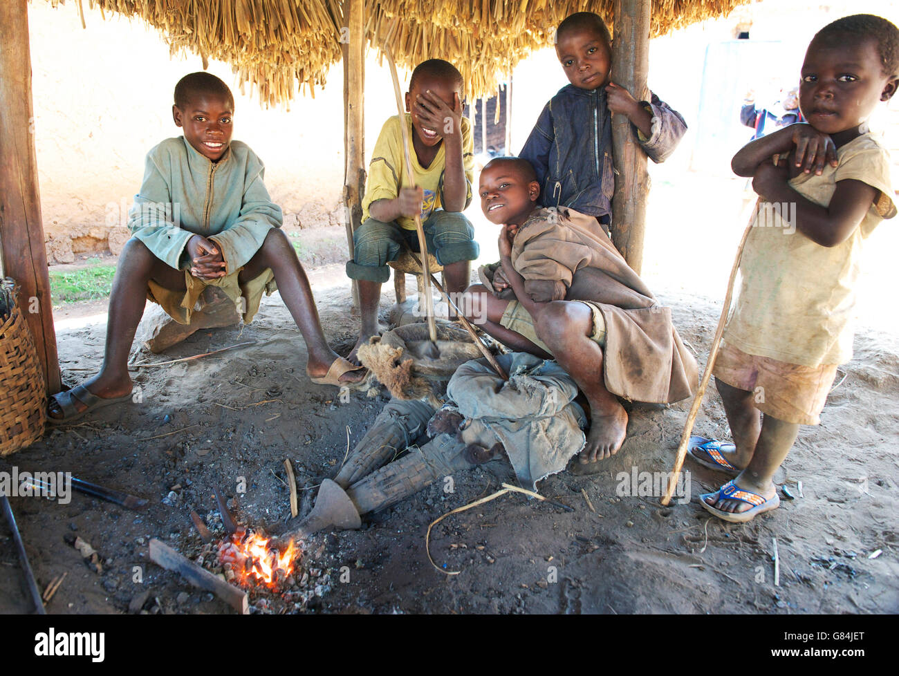 Group of Ugandan children gather under a shelter in he village centre, where they work with local blacksmiths Stock Photo