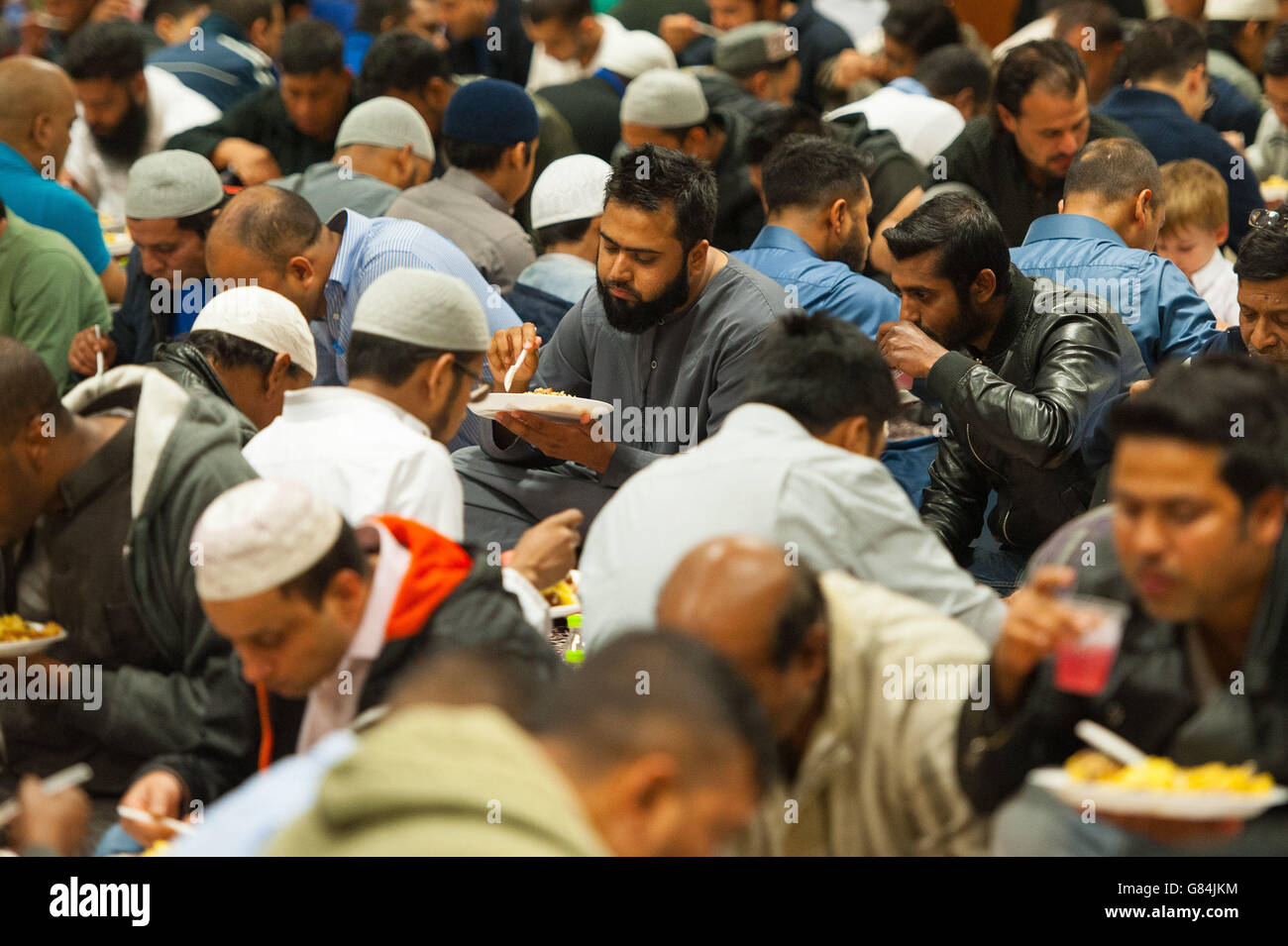 Muslim men eat Iftar, the evening meal to break fast during Ramadan, at the East London Mosque, in Whitechapel, London. Stock Photo