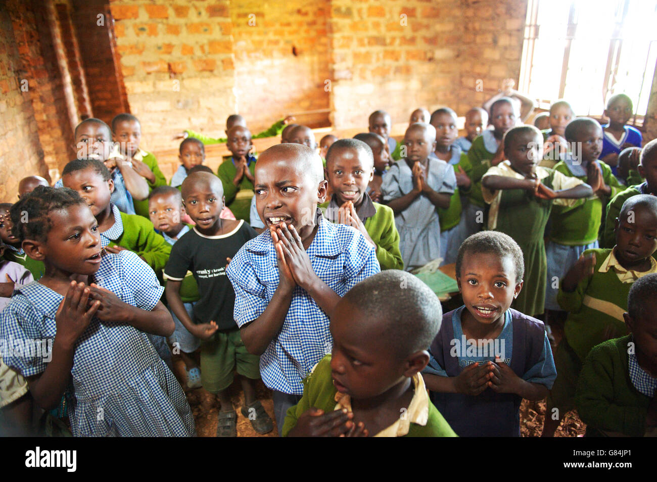 Group  of Ugandan school children in a rural African school gather for morning preys, looking focused and anxious Stock Photo