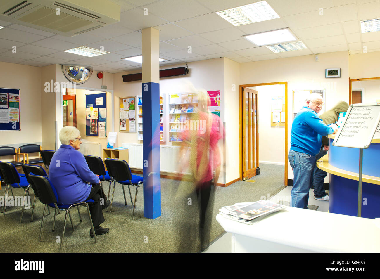 busy and somewhat hectic waiting room in GP health centre practice as patients register for appointments Stock Photo
