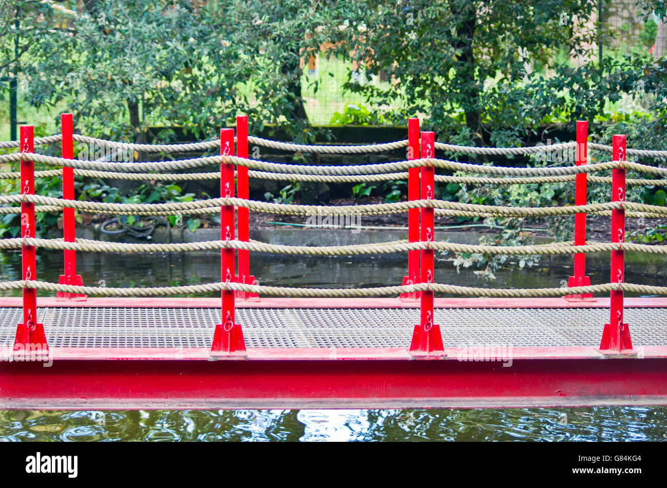 pedestrian bridge built in art wooden, red railing and hemp ropes in ...
