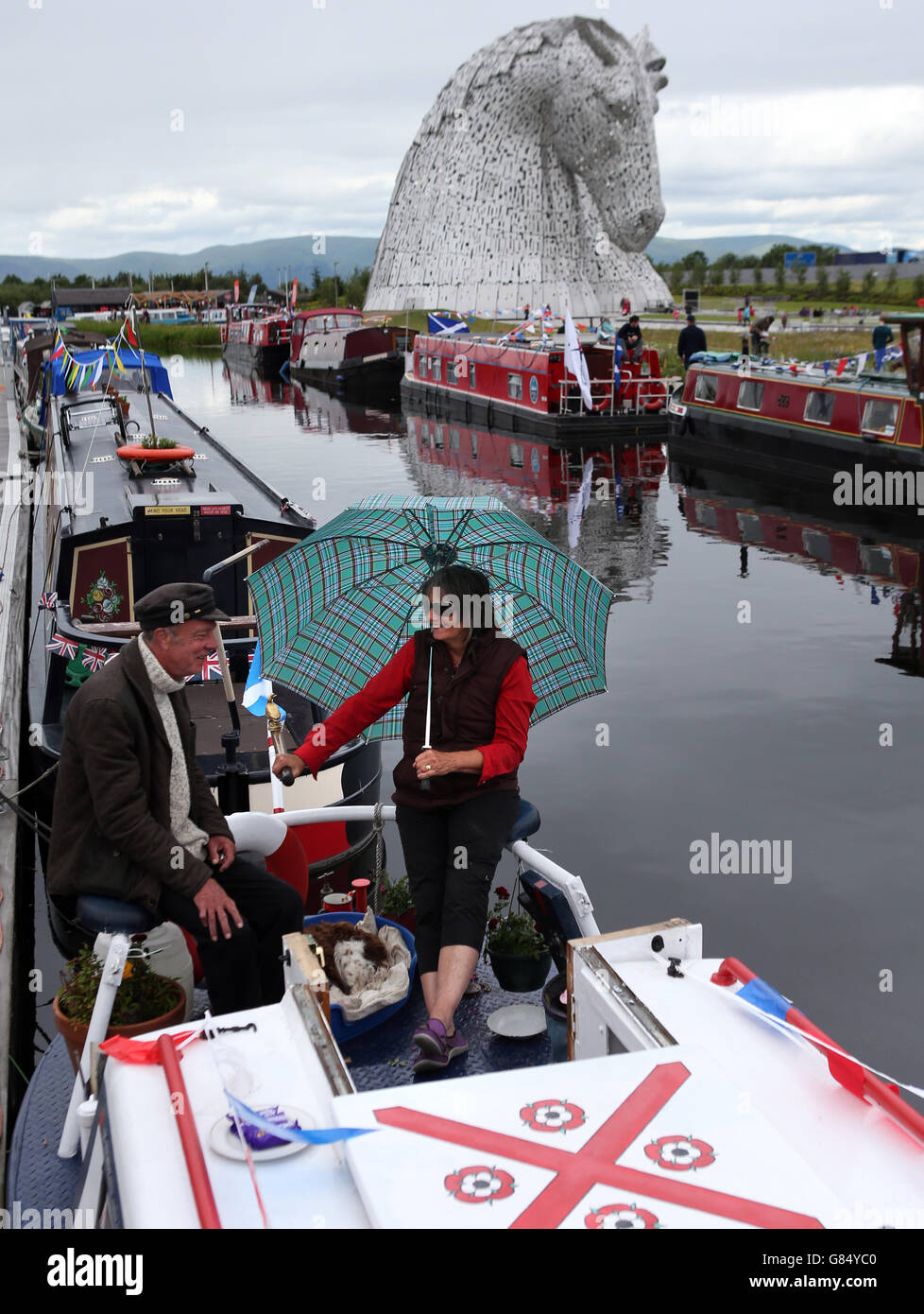 Boaters Dougie and Bernadette MacFarlane on their barge Pendle in front of The Kelpies on the Forth and Clyde Canal after the visitor attraction was officially opened by the Princess Royal. Stock Photo