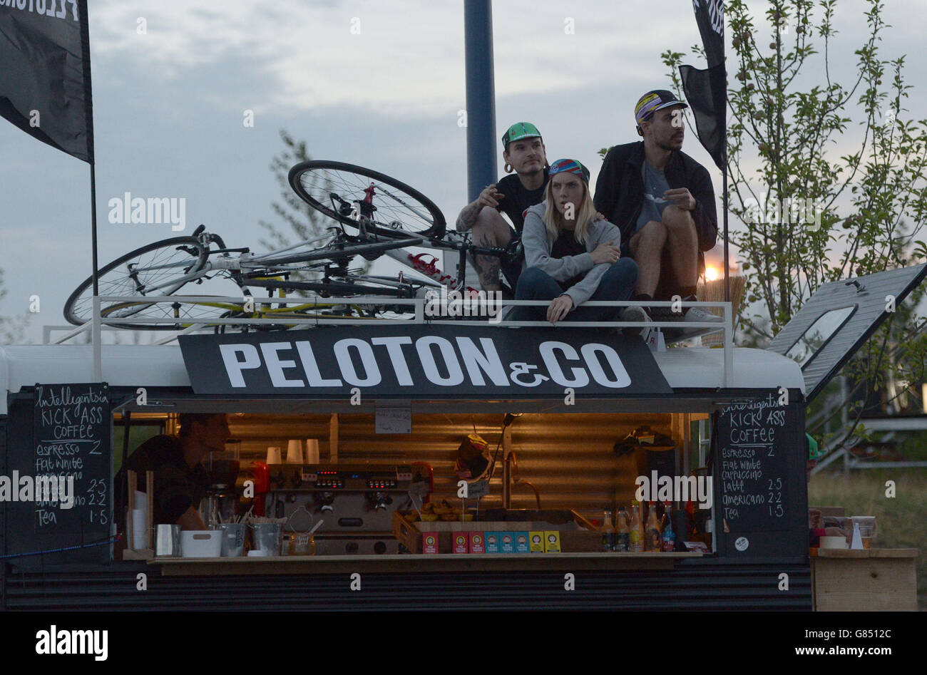 Spectators watch the action from the roof of a coffee van as cyclists compete in the Red Hook Criterium men's race at Greenwich Peninsula in London. Stock Photo