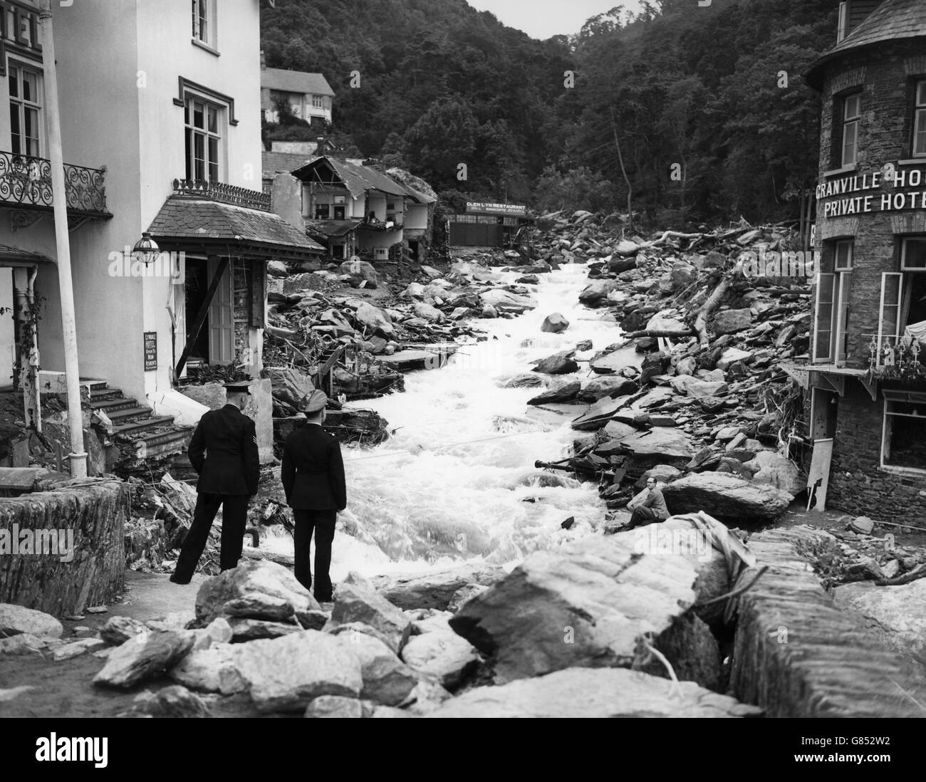Police stand on the remains of a bridge in Lynmouth, Devon, which has been devastated by floods. Stock Photo