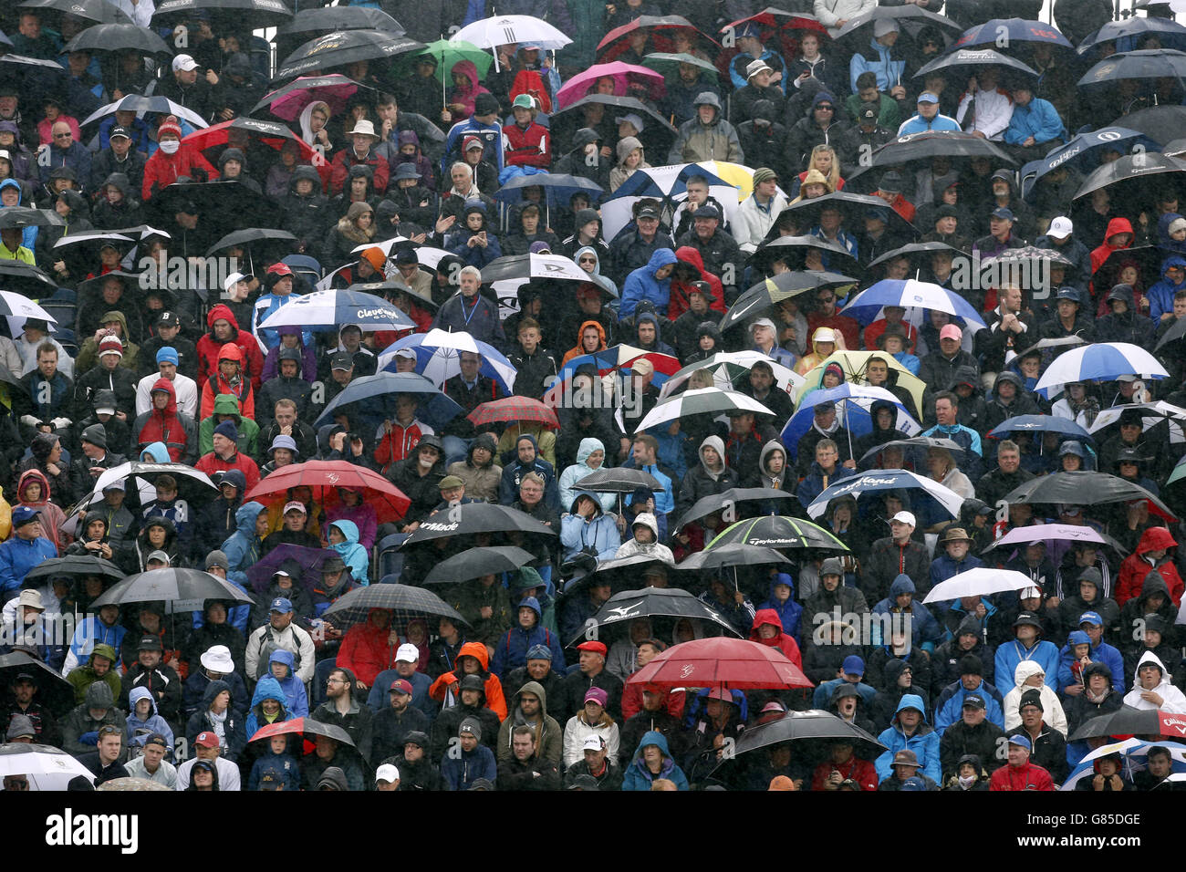 Spectators shelter from the rain under umbrellas as they sit in the stands during day five of The Open Championship 2015 at St Andrews, Fife. Stock Photo