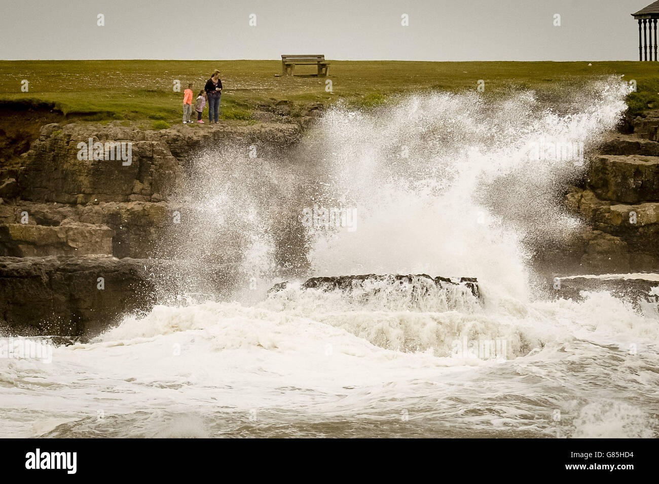People explore the rocks and coastline at Porthcawl, South Wales, where high winds are battering the UK. Stock Photo