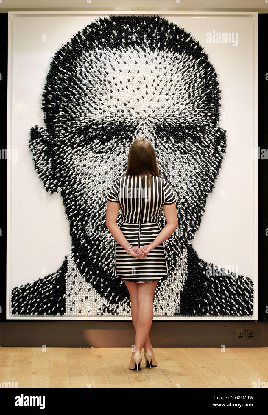A Christie's employee looks at 'Shoot to Kill' by Joe Black during a press preview for the third annual 'Out of the Ordinary' auction hosted by Christie's in South Kensington, London. Stock Photo