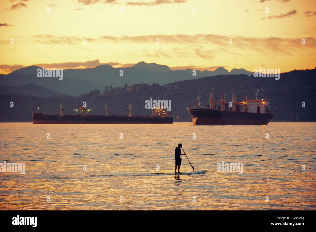 A man row boat in sea in Vancouver at sunset Stock Photo