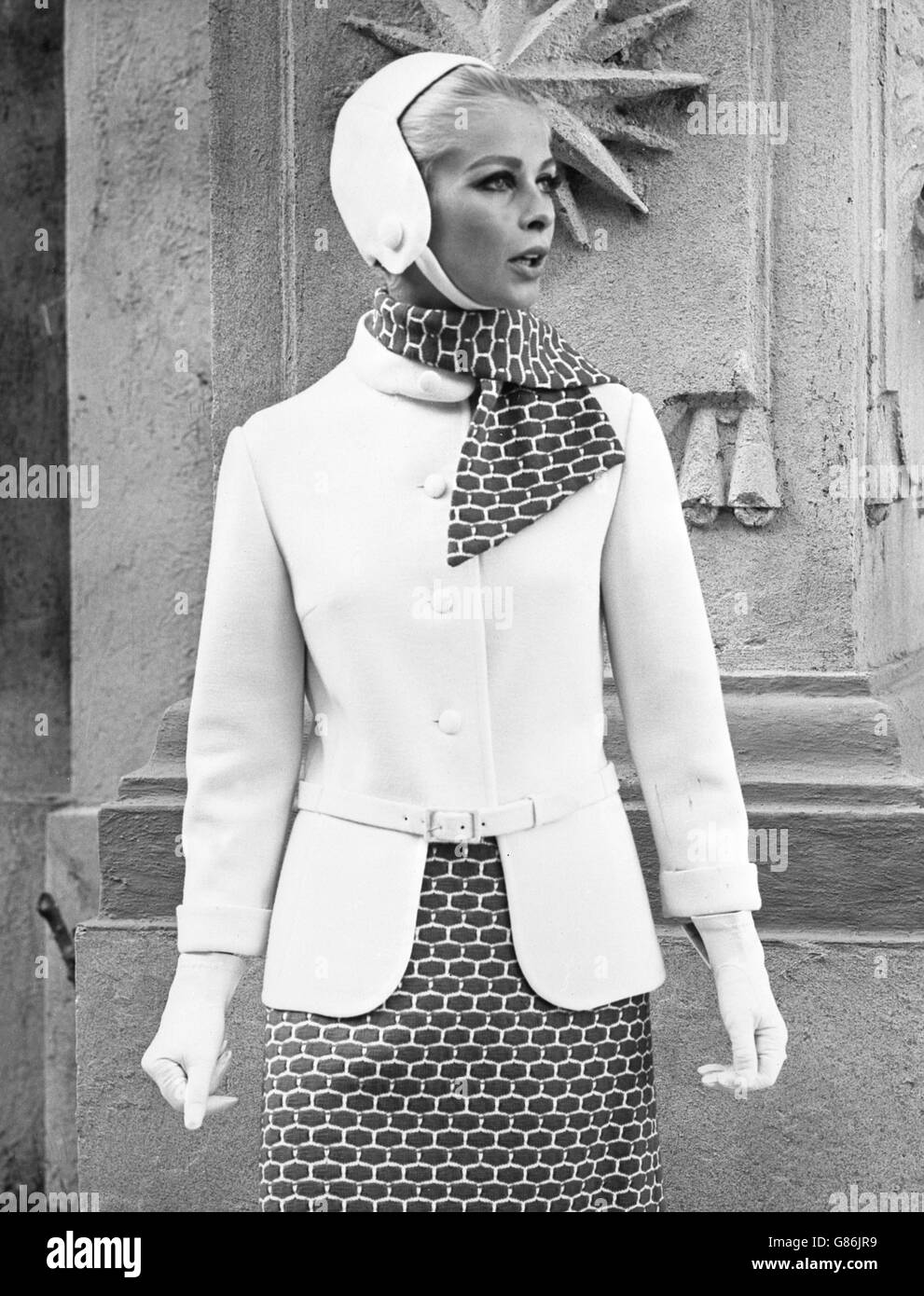 1960s Fashion - London. A model wears a suit that features a mustard-coloured mosaic stitch in white wool. Stock Photo