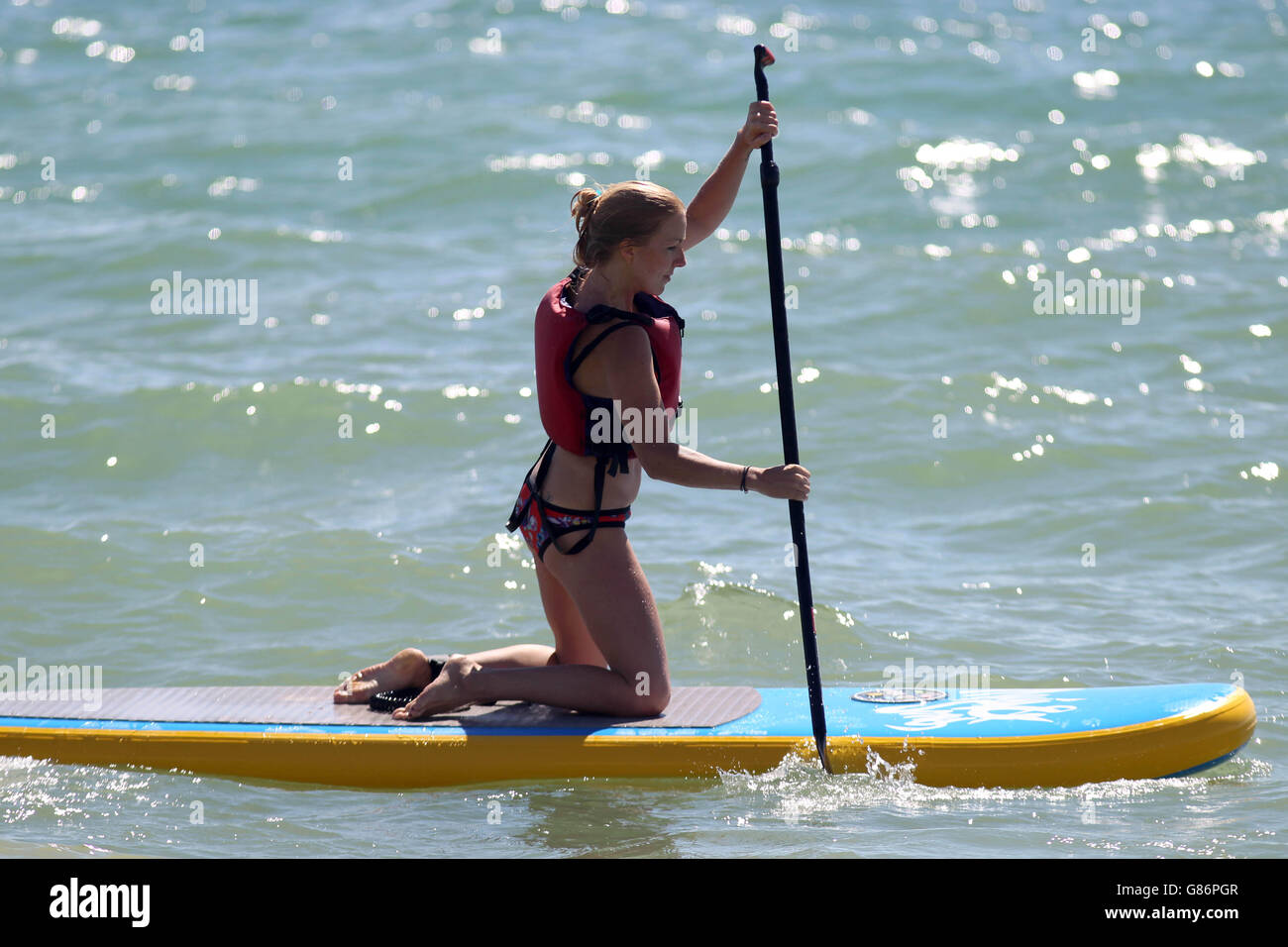 Paddle boarder the hot weather on the beach in brighton hires stock