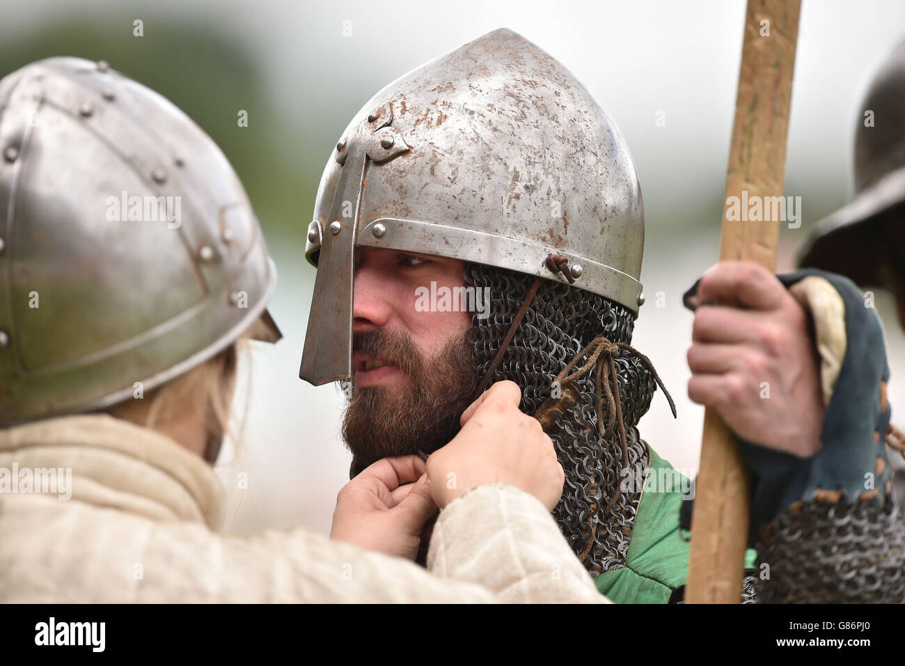A re-enactor has his helmet fastened before playing out the Battle of Evesham at Abbey Park in Evesham. Stock Photo
