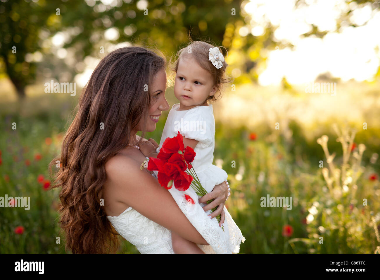 Woman holding daughter and poppy flowers Stock Photo