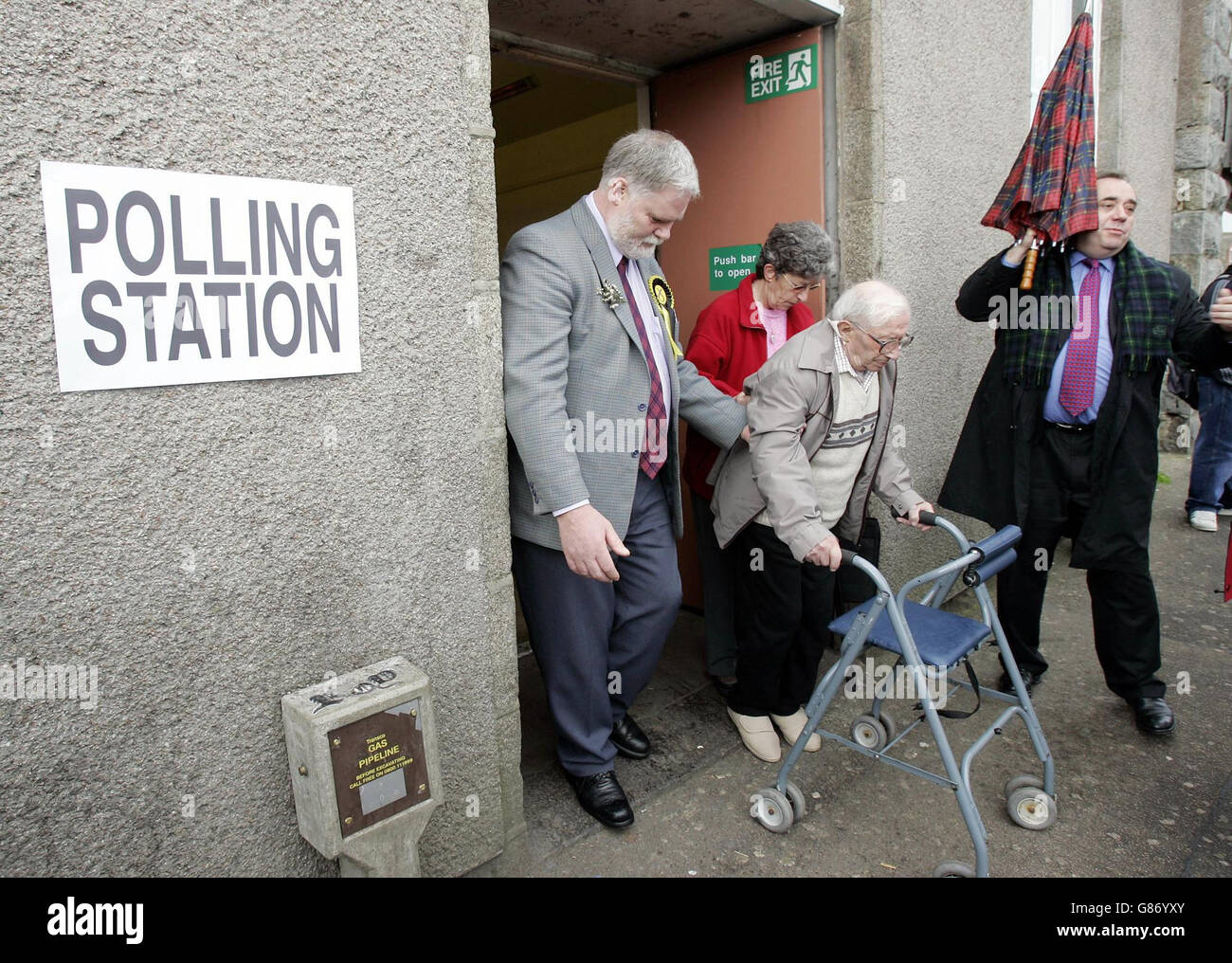 103-year-old Willie Thomson (centre) is helped after voting, with Scottish National Party leader Alex Salmond (right) standing by, at a polling station in the Aberdeenshire village of Mintlaw in the Banf and Buchan constituency. Stock Photo