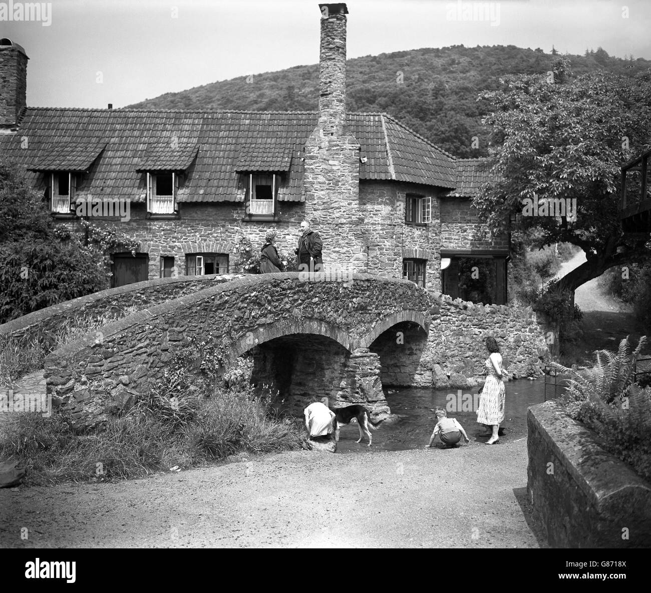 Children playing in the stream by the pack horse bridge at Allerford in Somerset. Stock Photo
