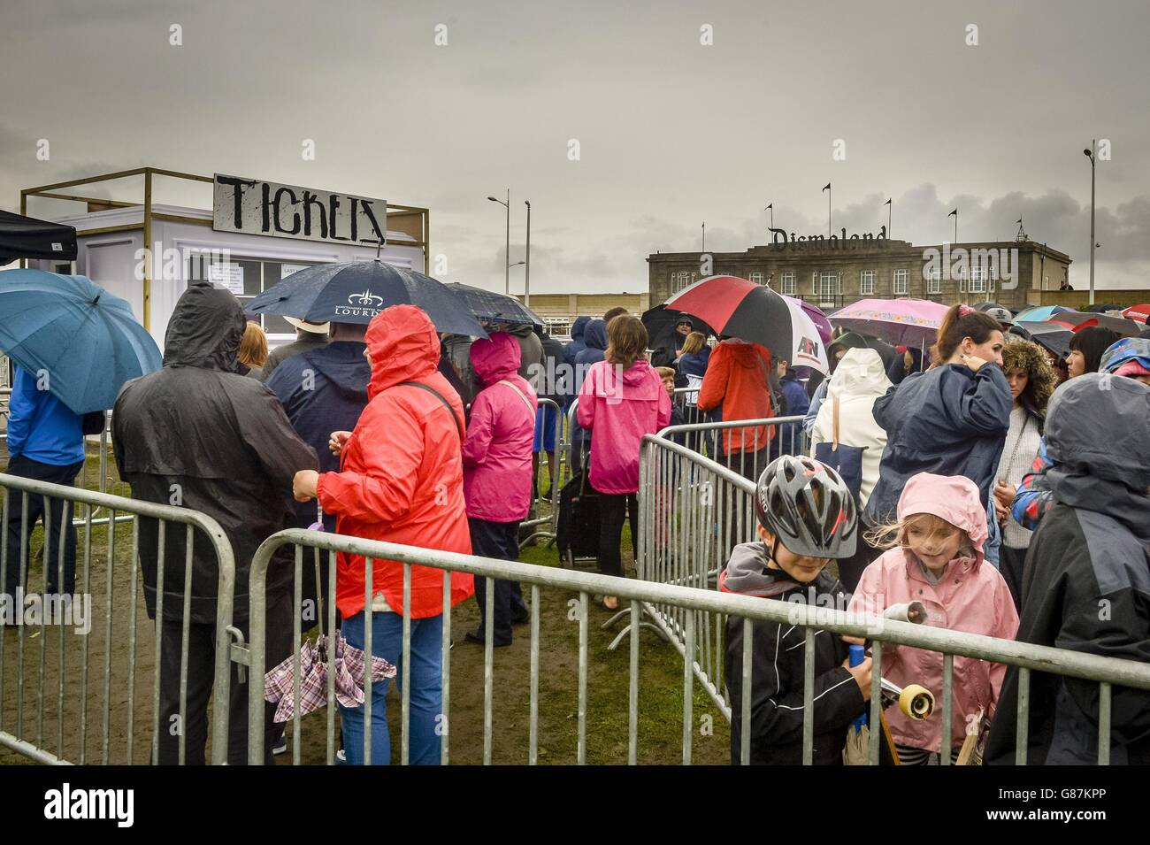 People queue in the rain to buy tickets for Banksy's exhibition theme park 'Dismaland' at Weston-super-Mare, Somerset. Stock Photo