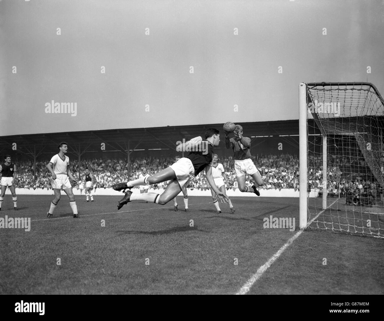 West Ham centre-forward Alan Sealey leaps in an attempt to head the ball from a corner kick, only to find Nottingham Forest goalkeeper Peter Grummitt a little to quick for him. Stock Photo