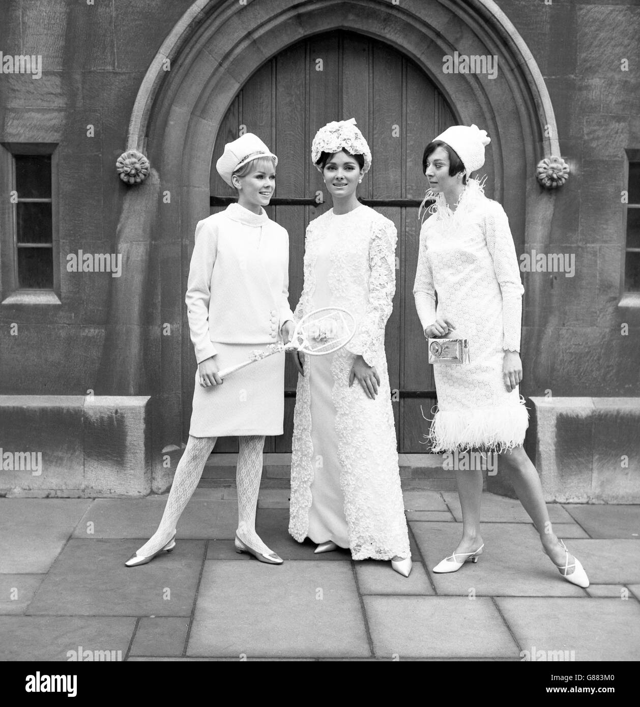 Models wear outfits from the Louis Young Living Doll collection, created for the mod-minded bride. Teresa Fray (left) models a suit in white Crimplene with polo neck blouse, white lace stockings and matching cap. Angela Pringle (centre) wears a two-piece outfit with a full-length sleeveless dress worn under a long scalloped-edge coat in white ribbon lace. Christine Harris shows a knee-length gown in guipure lace, trimmed with white ostrich. Stock Photo