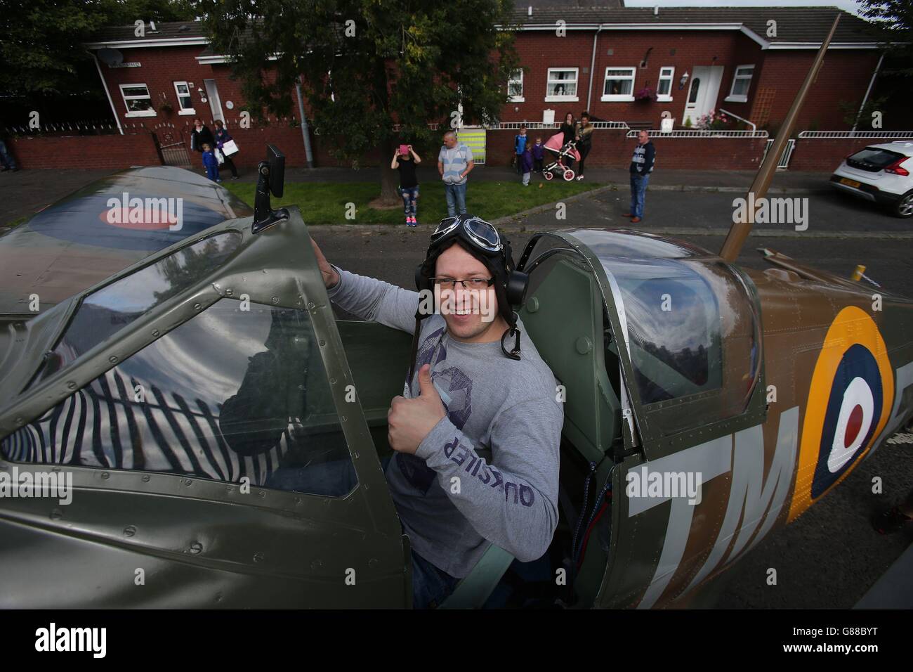 Polish man Michael Paluchiewicz sits in the cockpit of a replica Spitfire, during an unveiling of an anti-racism mural entitled Band as of Brothers, on a peace wall off the Shankil Road Belfast on the 75th anniversary of the Battle of Britain to mark the valiant efforts of Polish airmen, who were stationed in Northern Ireland. Stock Photo