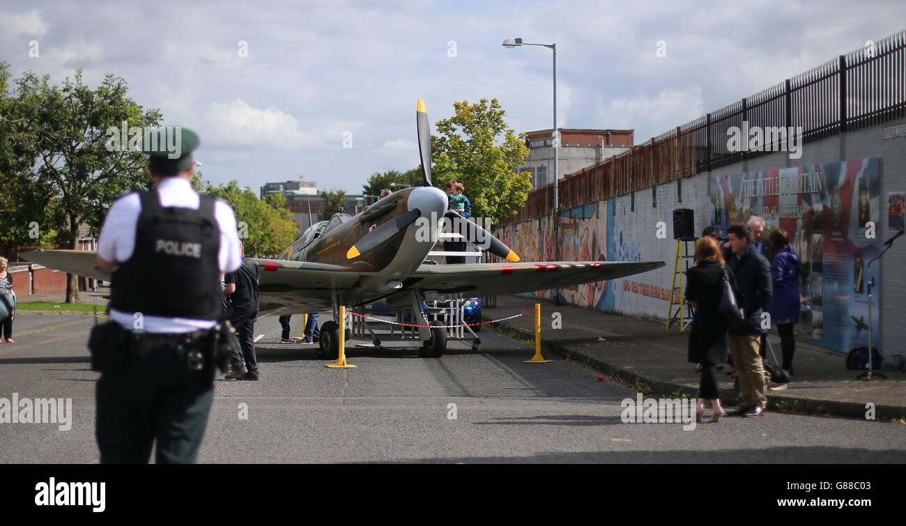 People view a replica of a Spitfire, during an unveiling of an anti-racism mural entitled Band as of Brothers, on a peace wall off the Shankil Road Belfast on the 75th anniversary of the Battle of Britain to mark the valiant efforts of Polish airmen, who were stationed in Northern Ireland. Stock Photo