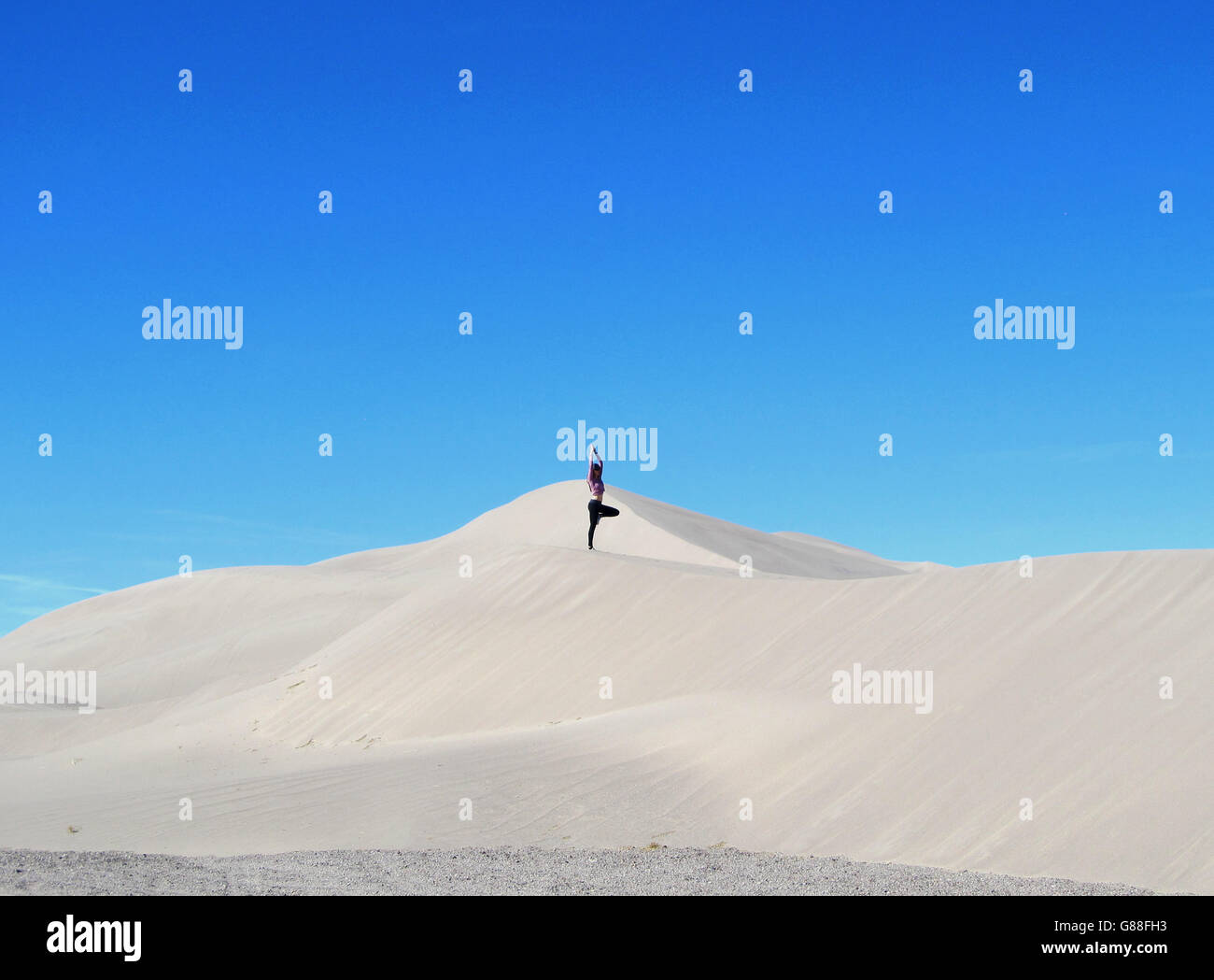 Women doing yoga tree pose on sand dunes Stock Photo - Alamy
