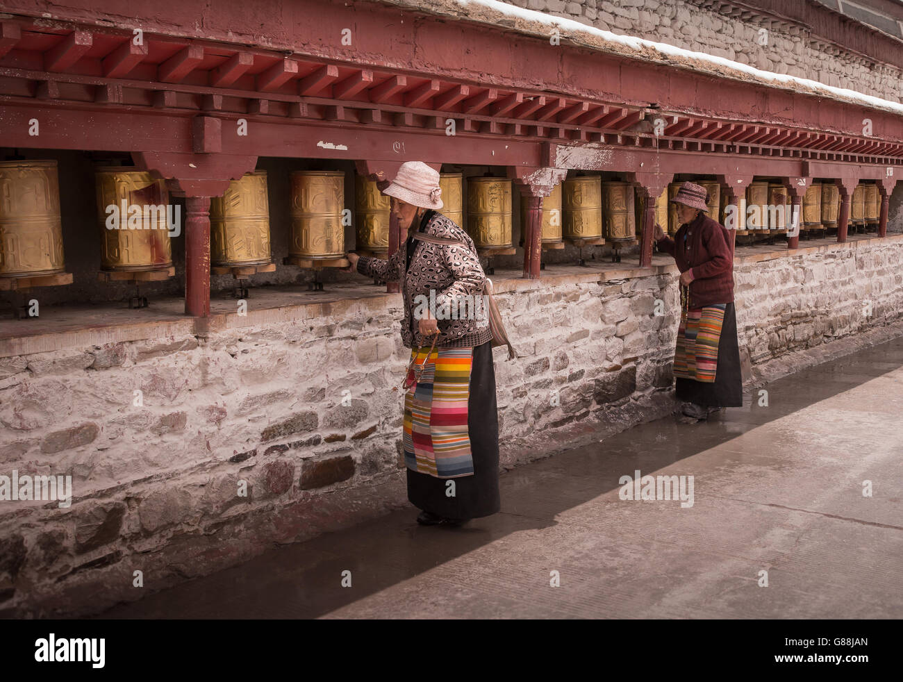 SHIGATSE, TIBET – MAY 2016 - Two women spin prayer wheels at a Kora circuit around Tashi Lhanpo monastery in Shigatse, Tibet. Stock Photo