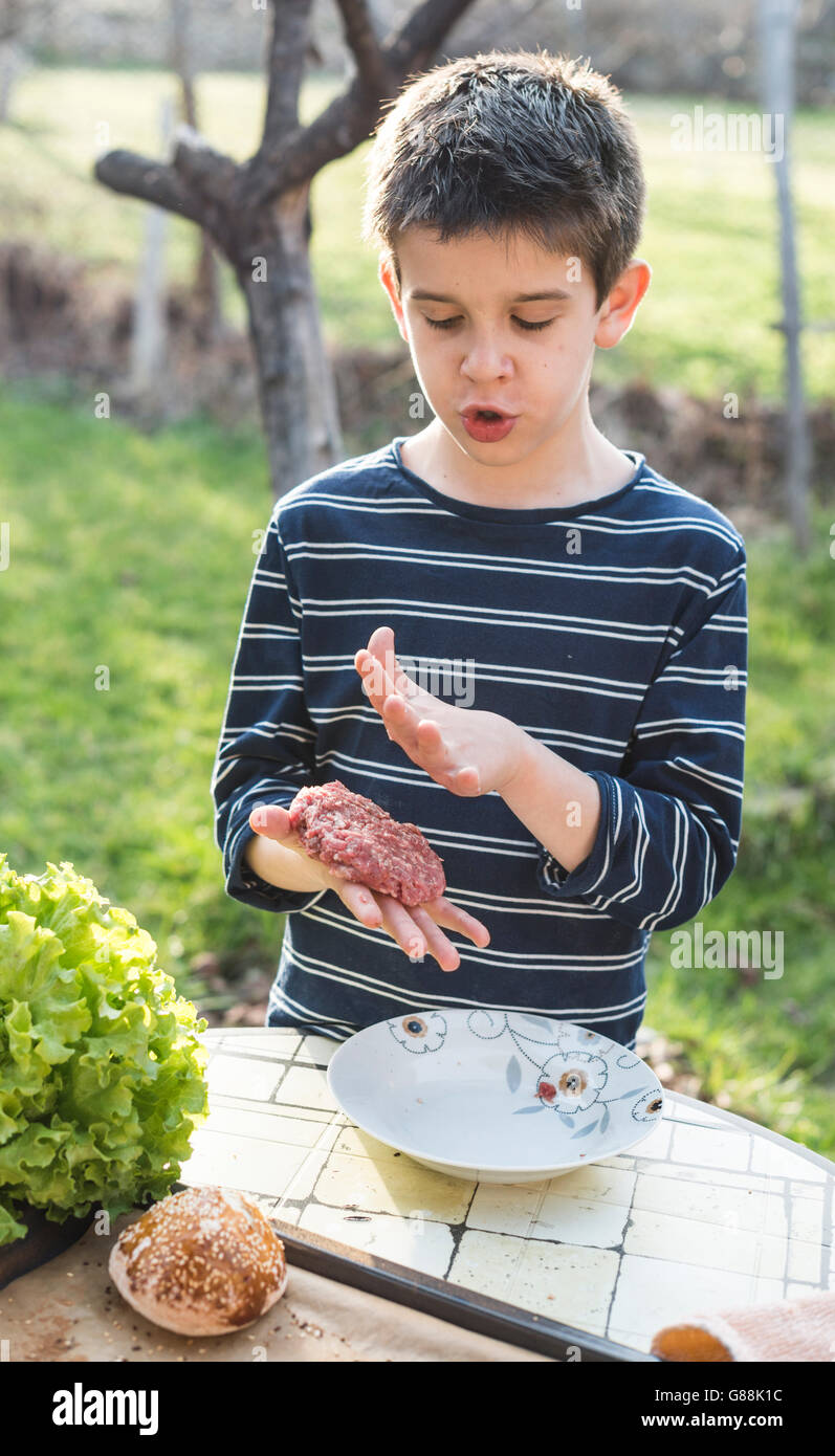 Boy making homemade burgers in the garden Stock Photo
