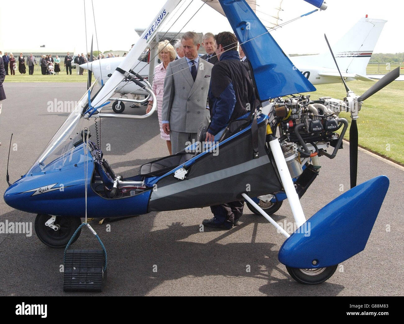 The Prince of Wales takes a close look at a microlight aircraft whilst talking with Chris Bailey, 25, Chief Flying Instructor of microlights at Kemble Flying Club, when he and the Duchess of Cornwall visited Kemble Airfield. A former RAF /UASF base dating back to 1936, it has now made the transition to a busy civilian airfield. Stock Photo