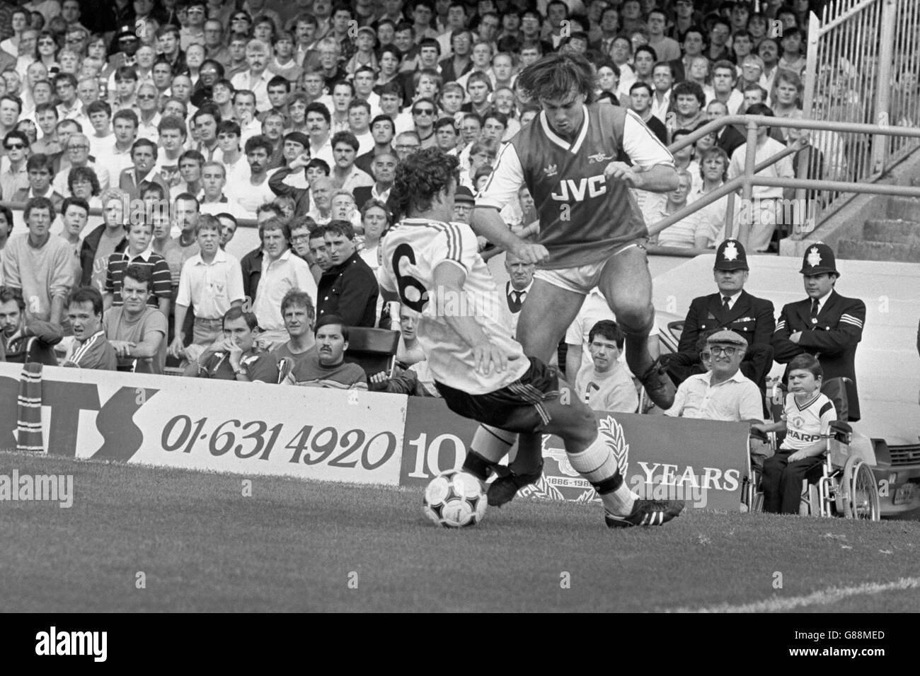 Arsenal's Charlie Nicholas (r) tries to slip the ball past the tackle from Manchester United's Kevin Moran (l) Stock Photo