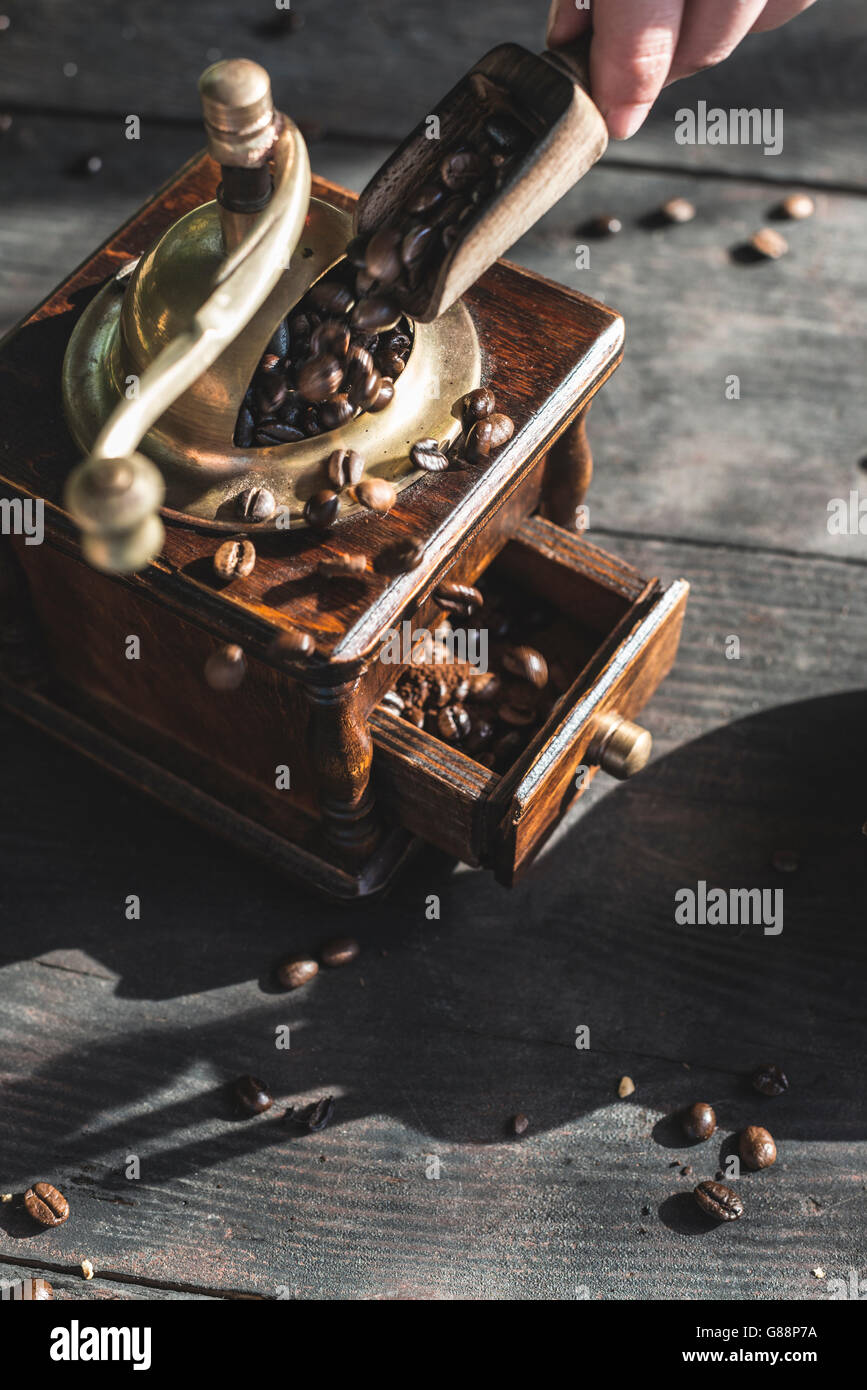 Woman putting coffee beans in vintage coffee grinder Stock Photo