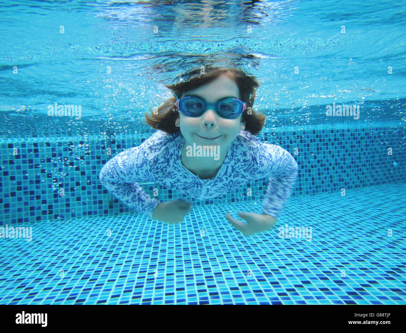 Girl swimming underwater in swimming pool Stock Photo