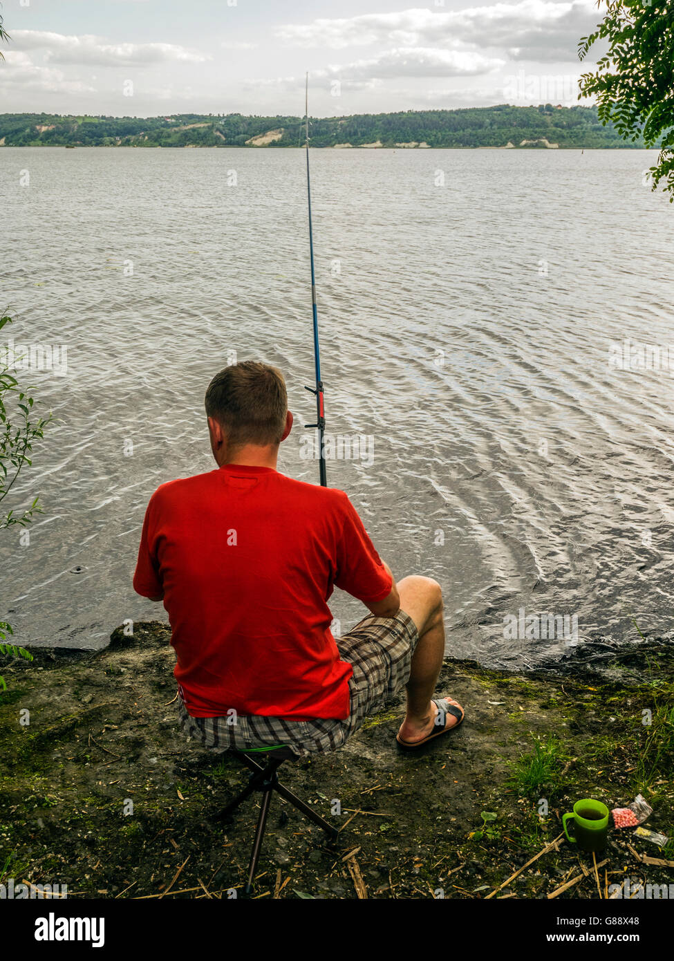 Man sitting by river fishing Stock Photo