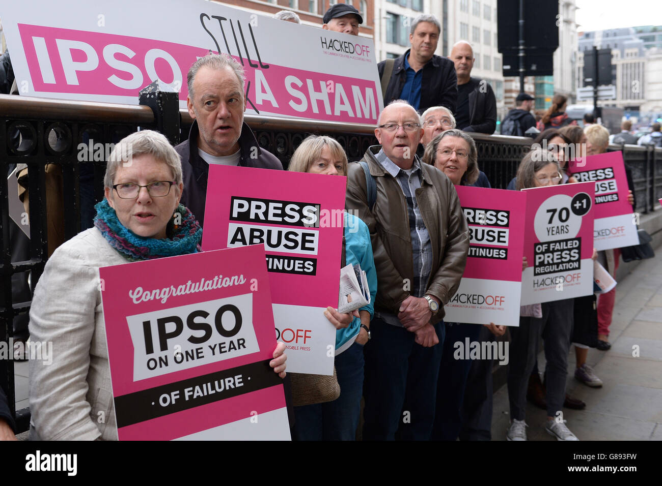 Hacked Off campaigners hold banners in a protest about the lack of effectiveness of the regulator Independent Press Standards Organisation (IPSO) a year after it was formed, outside their offices in London. Stock Photo