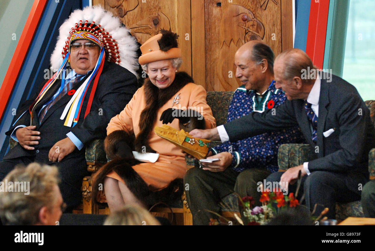 Queen Elizabeth II is shown some moccasins by the Duke of Edinburgh after he was presented with them during their visit to the First Nations University in Regina. The city, which is celebrating centennial, welcolmed the Queen on the first day, of her eight day state visit to Saskatchewan and Alberta. The Queen sits between First Nation Indians, Cree Chief, Alphonse Bird (left) of the Federation of Indian Nations and Doctor Eber Hampton. Stock Photo
