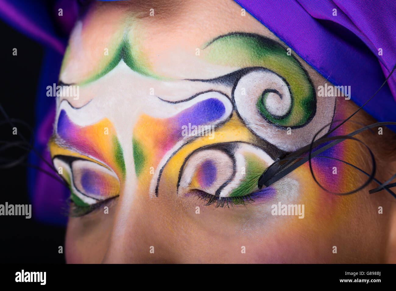 Female model portrait with tribal creative make-up swirl and purple turban Stock Photo