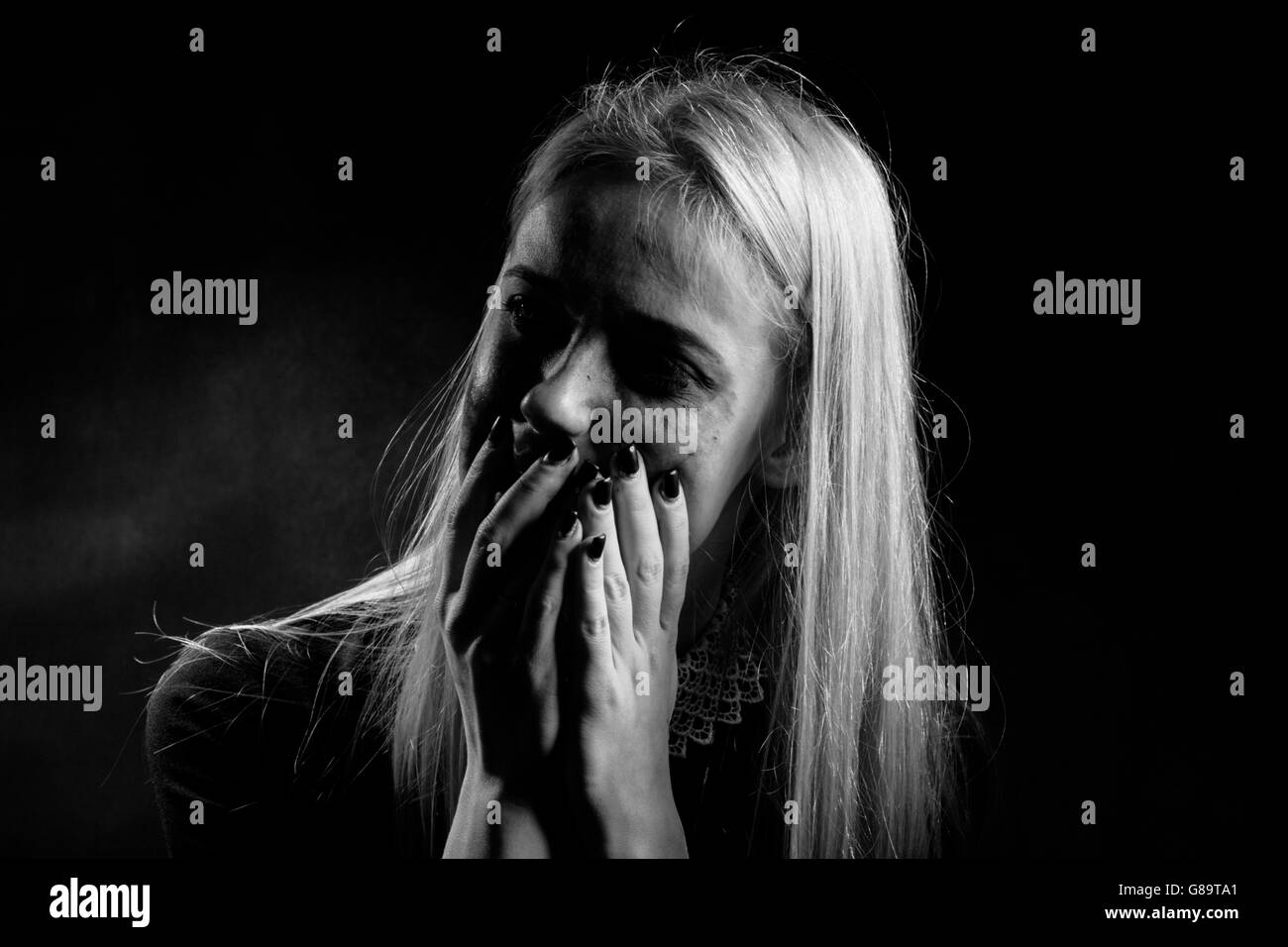 woman with smeared cosmetics crying on black background, monochrome Stock Photo